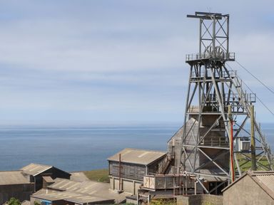 A coastal view of industrial mining buildings and a metal mining framework at Little Victory in Pendeen