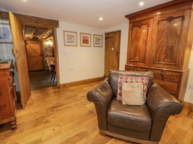 A room with a brown leather armchair with cushions wooden furniture wooden floor and two wooden doors at Ysgubor in Dinas Mawddwy near Dolgellau