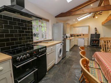 A kitchen with black and white appliances wooden countertops and wooden chairs at Ysgubor in Dinas Mawddwy near Dolgellau