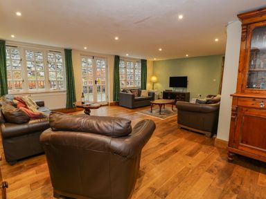 A living room with leather sofas and wooden furniture near windows at Ysgubor in Dinas Mawddwy near Dolgellau