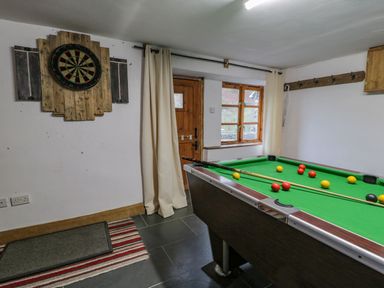 A game room with a pool table and a dartboard on the wall at Ysgubor in Dinas Mawddwy near Dolgellau