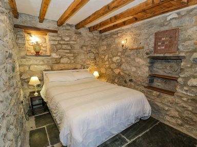A bedroom with stone walls wooden beams and a double bed at Ysgubor in Dinas Mawddwy near Dolgellau