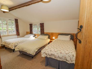 A bedroom with three single beds and two windows at Ysgubor in Dinas Mawddwy near Dolgellau