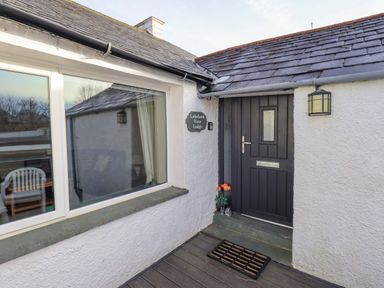 An entrance door with a doormat and flowers next to it and a window on the left at Lakeland View Lodge in Keswick