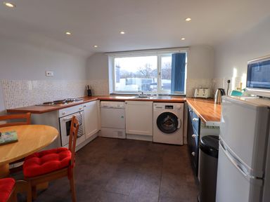 A kitchen with appliances including a washing machine, dishwasher, oven, microwave, and refrigerator at Lakeland View Lodge in Keswick