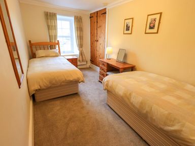 A bedroom with two single beds a window and wooden furniture at Lakeland View Lodge in Keswick