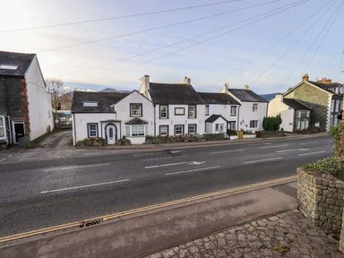 A street view of white terraced houses with slate roofs and stone walls in a village at Lakeland View Lodge in Keswick