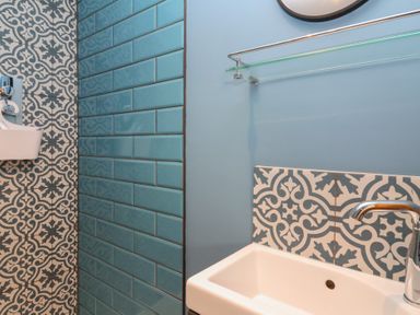 A bathroom with a white sink blue subway tiles and patterned tiles at Curlew Cottage in North Curry near Taunton