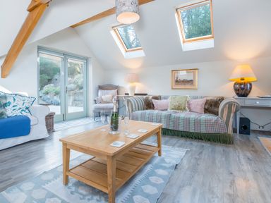 A living room with sofas a wooden coffee table and skylights at Leeward Cottage in Cosheston near Pembroke Dock