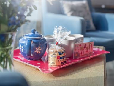A blue teapot cups and a packet of welsh cakes on a pink polka dot tray on a table in a living room at Leeward Cottage in Cosheston near Pembroke Dock