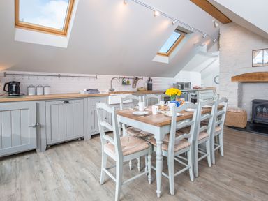 A kitchen with a dining table set with plates and cups under skylights at Leeward Cottage in Cosheston near Pembroke Dock