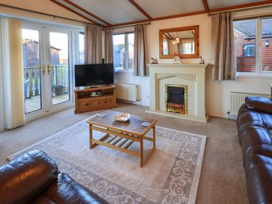 A living room with a coffee table TV and fireplace at Lavender Lodge in South Lakeland Leisure Village