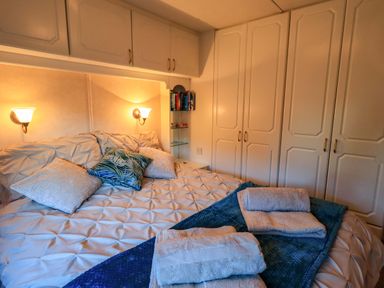 A bedroom with a bed towels on a blue blanket and wardrobes at Lavender Lodge in South Lakeland Leisure Village