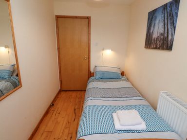 A small bedroom with a single bed a wooden door a wall mirror and a wall painting at Waters Edge in Embleton