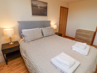 A bedroom with a bed and two bedside tables with lamps at Waters Edge in Embleton