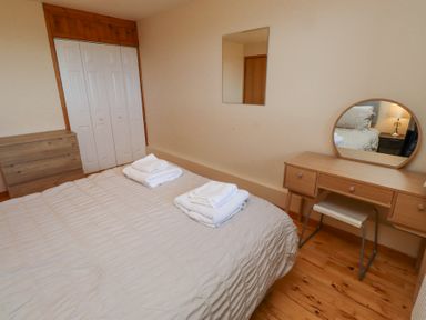 A bedroom with a bed and towels on it a dresser a vanity table with a mirror and a chair at Waters Edge in Embleton