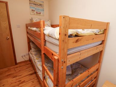 A bedroom with wooden bunk beds and a painting on the wall at Dunstanburgh View in Embleton
