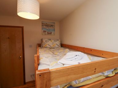 A bedroom with a single wooden bed with folded towels and a painting on the wall at Dunstanburgh View in Embleton