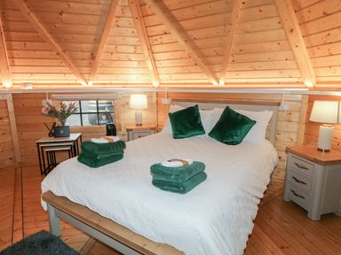 A bedroom with a large bed with white bedding and green pillows inside a wooden cabin at The Hideaway in Dungiven Londonderry