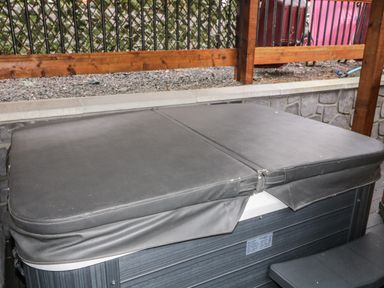 A covered hot tub with wooden railing and gravel area behind at The Hideaway in Dungiven Londonderry