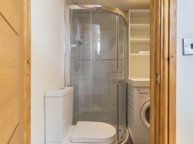 A bathroom with a toilet a corner shower and a washing machine at Upper Calffield Barn Camrose near Haverfordwest