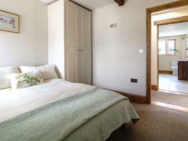 A bedroom with a bed a wardrobe and a view into a bathroom at Upper Calffield Barn Camrose near Haverfordwest