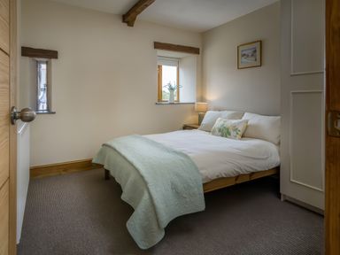 A bedroom with a double bed nightstand lamp and window at Upper Calffield Barn Camrose near Haverfordwest