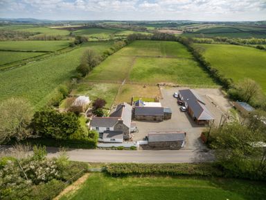 A rural farm property with multiple buildings surrounded by fenced pasture fields and green farmland at Upper Calffield Barn Camrose near Haverfordwest