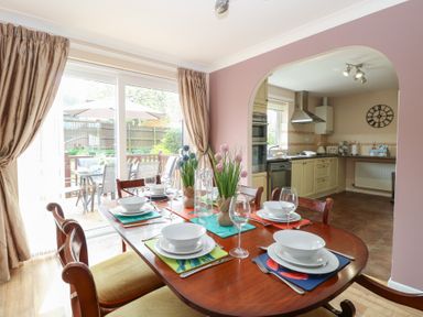 A dining room with a set table and a view into a kitchen through an archway at White Lion Retreat in Cromer