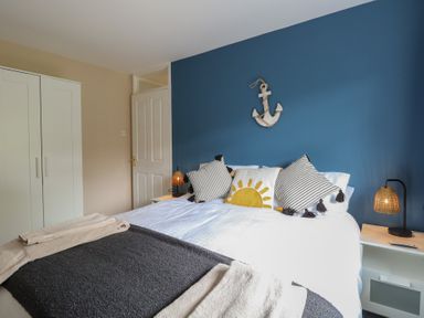 A bedroom with a bed pillows and blankets a white wardrobe and bedside tables with lamps at White Lion Retreat in Cromer