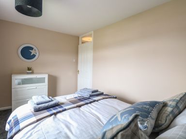 A bedroom with a bed with pillows and folded towels a white chest of drawers and a door at White Lion Retreat in Cromer