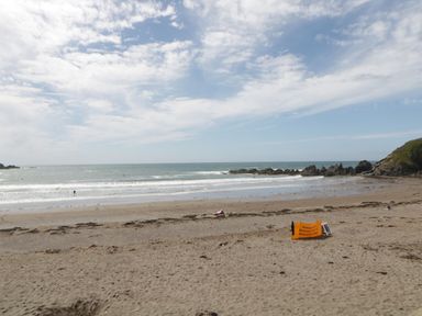 A sandy beach with a safety sign and ocean waves at 3 Cumberland Cottages in Ringmore