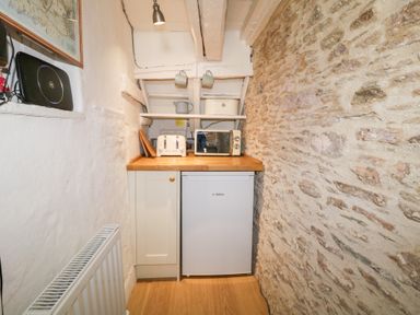 A small kitchen area with a toaster microwave fridge and wooden countertop at 3 Cumberland Cottages in Ringmore