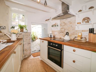 A kitchen with wooden countertops an oven a kettle and shelves with kitchen items at 3 Cumberland Cottages in Ringmore