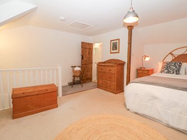 A bedroom with a bed a wooden chest a wooden dresser and a chair at 3 Cumberland Cottages in Ringmore