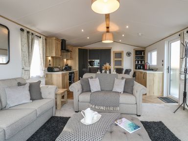 A living room with sofas and a coffee table next to a kitchen in Dorchester in Broomholm near Mundesley