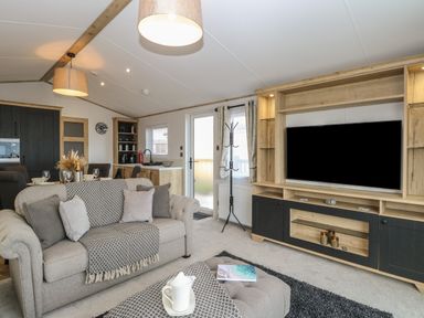 A living room with a sofa and television next to a kitchen and dining area at Dorchester in Broomholm near Mundesley
