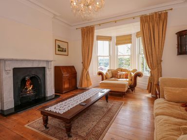 A living room with a fireplace wooden coffee table sofas and a bay window at Fir Grove in Menai Bridge