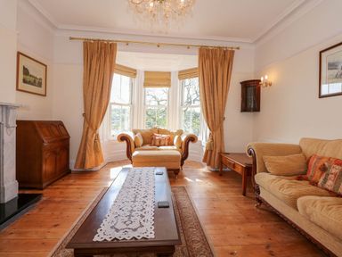 A living room with a sofa armchair wooden coffee table and curtains at Fir Grove in Menai Bridge