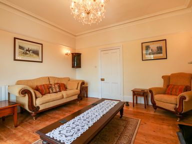 A living room with sofas a coffee table and framed pictures on the walls at Fir Grove in Menai Bridge