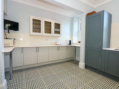 A kitchen with cabinets a microwave toaster coffee maker and wall-mounted tv at Fir Grove in Menai Bridge