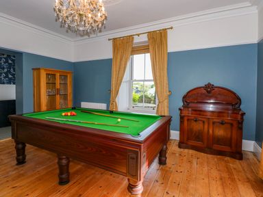 A room with a pool table a wooden cabinet and a wooden sideboard with blue walls and wooden floor at Fir Grove in Menai Bridge