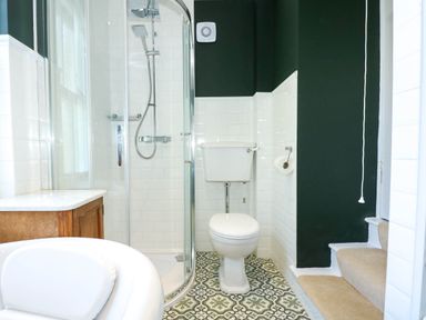 A bathroom with a toilet shower enclosure bathtub and stairs at Fir Grove in Menai Bridge