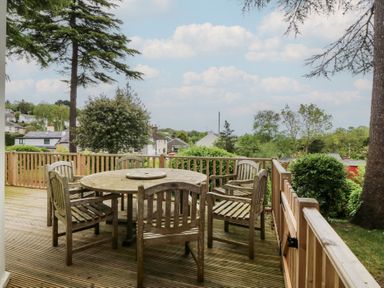 An outdoor space with a wooden table and chairs at Fir Grove Menai Bridge