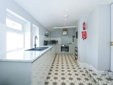 A kitchen with patterned floor tiles and appliances along one side at The Fir Grove Annex in Menai Bridge