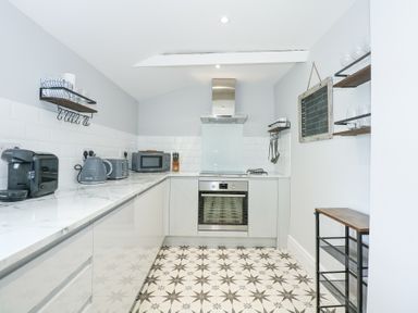 A kitchen with countertop appliances shelves and a patterned floor at The Fir Grove Annex in Menai Bridge