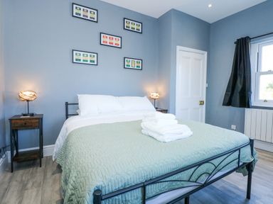 A bedroom with a double bed two bedside tables with lamps and framed pictures on the wall at The Fir Grove Annex in Menai Bridge