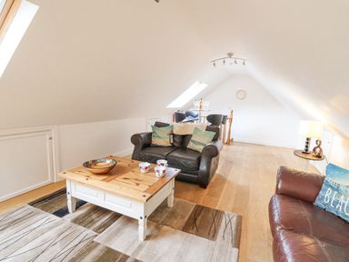 A loft living room with leather sofas wooden coffee table and bar stools at Trevone in Goodwick