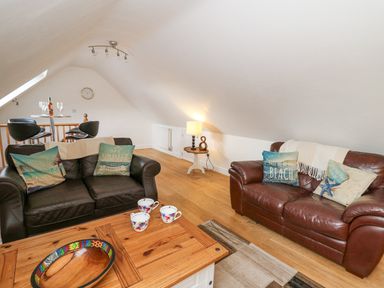 A living room with two leather sofas wooden coffee table with cups and bowl and a lamp on a side table at Trevone in Goodwick