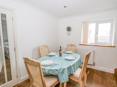 A dining room with a table set for four with plates and glasses near a window at Trevone Goodwick